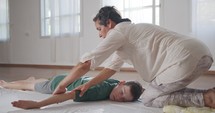 Shiatsu treatment. Masseuse giving treatment to a young boy, pressing on his back and neck