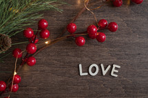 red berries and fairy lights on a wood background and word love 