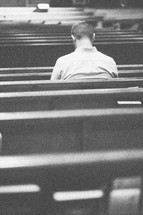 Man praying in a church pew.