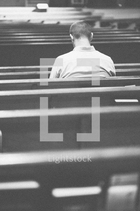 Man praying in a church pew.