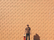 man standing in front of a patterned exterior wall 