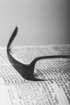 Reading glasses on pages of open Bible.