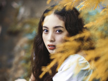 a headshot of a young woman in an autumn forest 