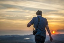 a man walking with his camera at sunset 