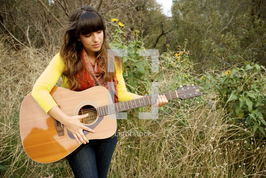 woman playing her guitar outdoors 