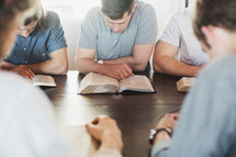 men reading Bibles and praying at a Bible study.
