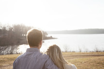 couple standing together by a lake 