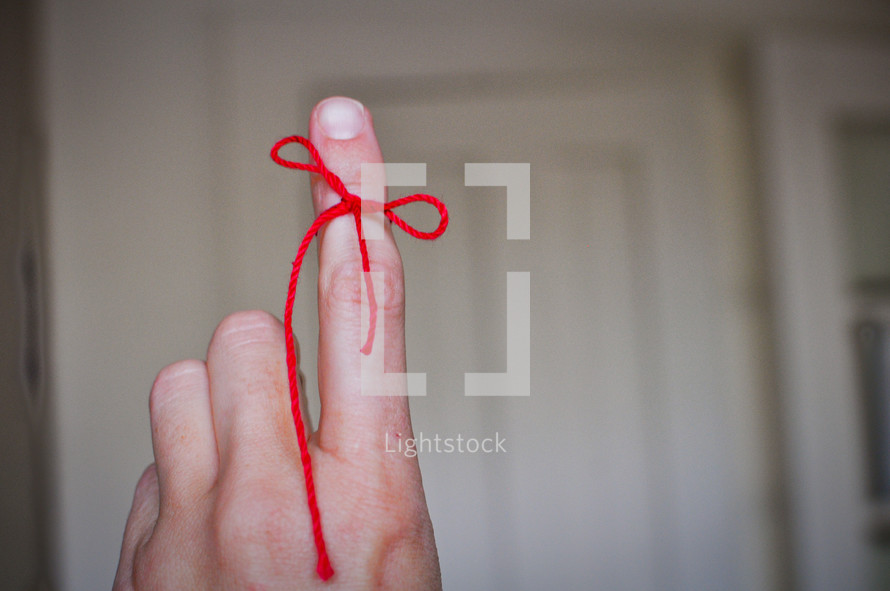 A finger tied with red string to serve as a reminder.