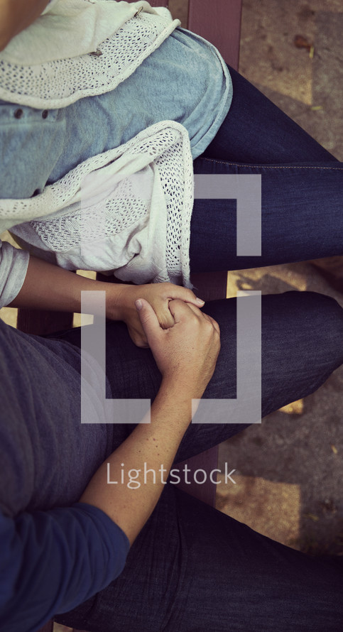 holding hands sitting on a park bench 