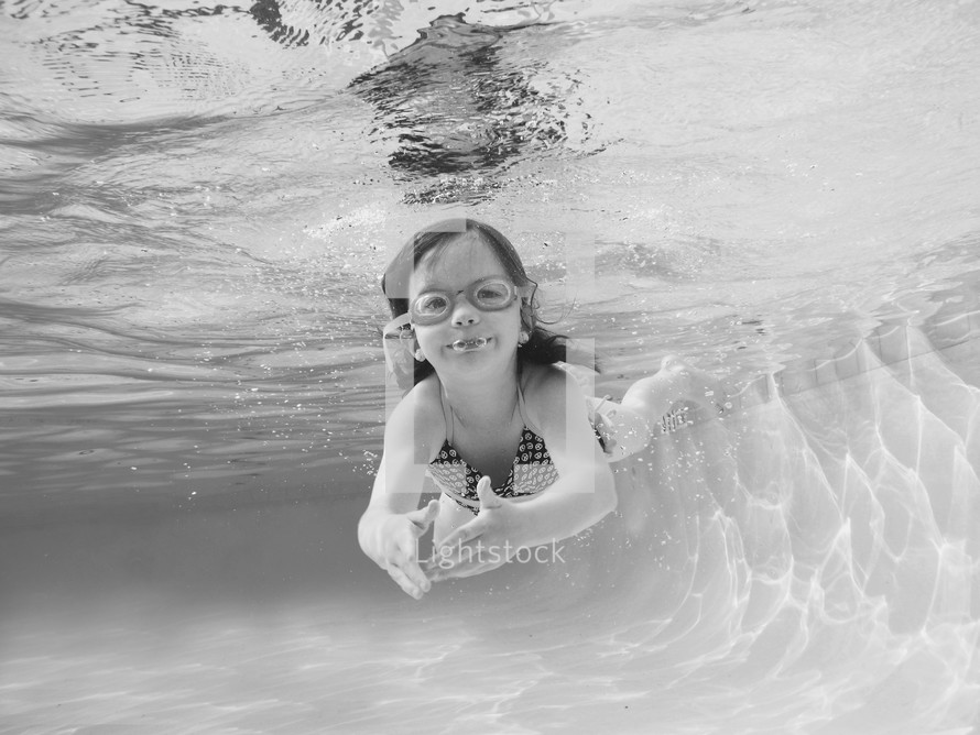 a child in goggles swimming under water 