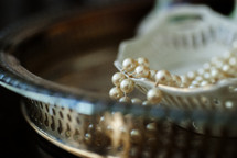 Pearls draped over an antique tray.