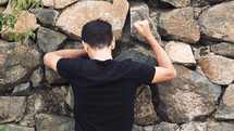 a man pounding his fist against a stone wall 