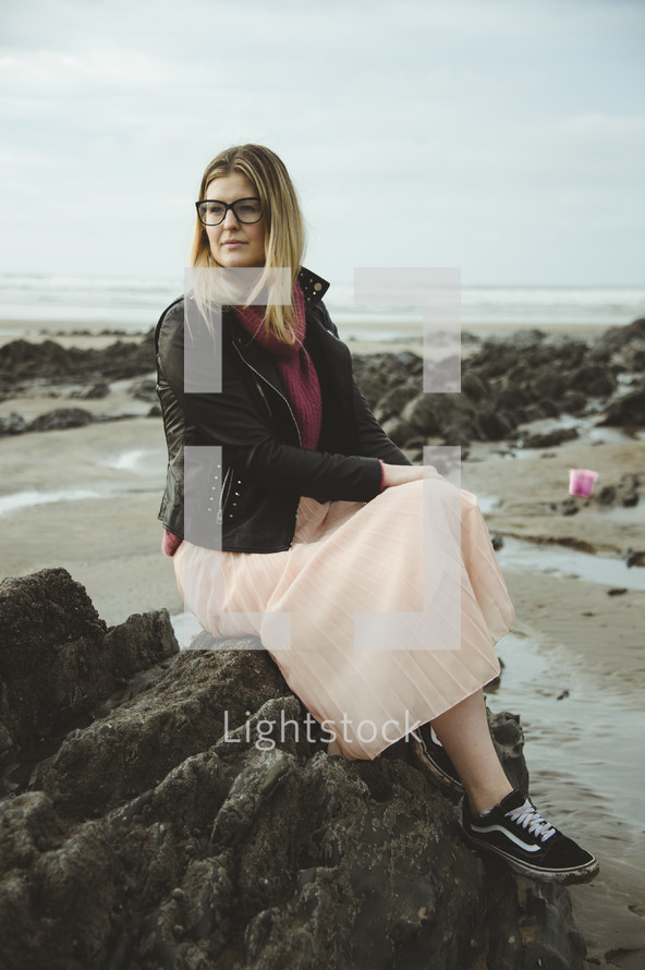 a woman sitting on a rock on a beach 