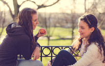 teen girls in conversation sitting outdoors 