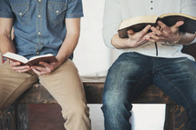 Two men sitting with open Bibles. 