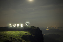 playing with light - the word love at the top of a cliff at night 