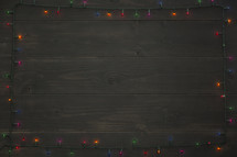 wood background with border of colored Christmas lights.