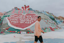 a man walking by a painted rock with the words god is love 