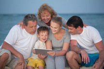 Happy big family with tablet PC on the beach