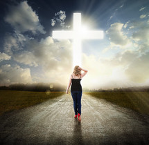 Woman walking in the middle of the road toward the light of Christ.