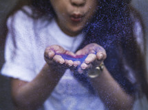 a young woman blowing glitter 