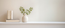 Home interior. Ceramic vase with eucalyptus branches and books on table. White wall background. Copy space.