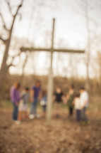 group holding hands and praying around a cross outdoors 