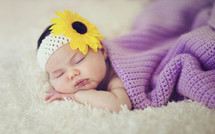 a newborn girl sleeping under a blanket 