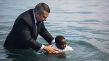 Baptism. A white Pastor baptize a little black kid in the water