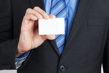 businessman in a suit holding a blank business card 