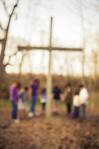holding hands in prayer around a cross