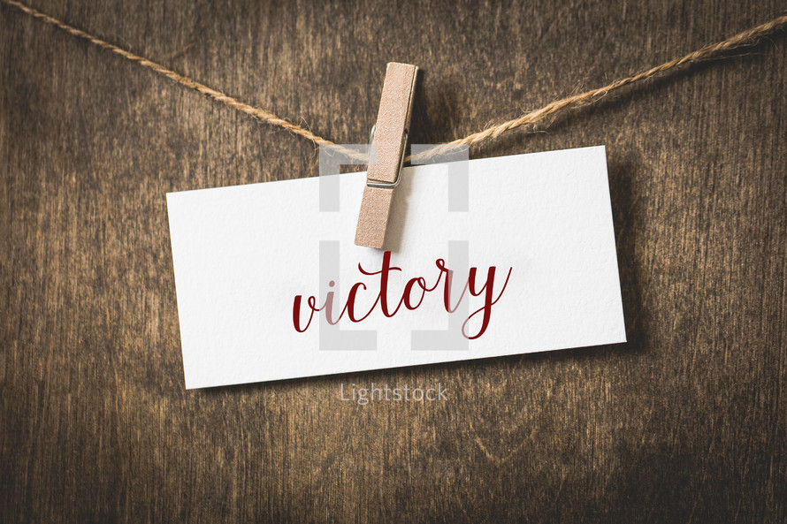 word victory on white card stock hanging from a clothespin on a clothesline 