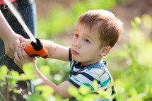 a boy holding a watering hose in a garden 
