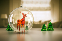 glass reindeer ornament and trees 
