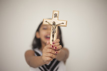 a young girl holding up a crucifix with joy