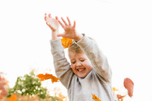 a child playing in fall leaves 
