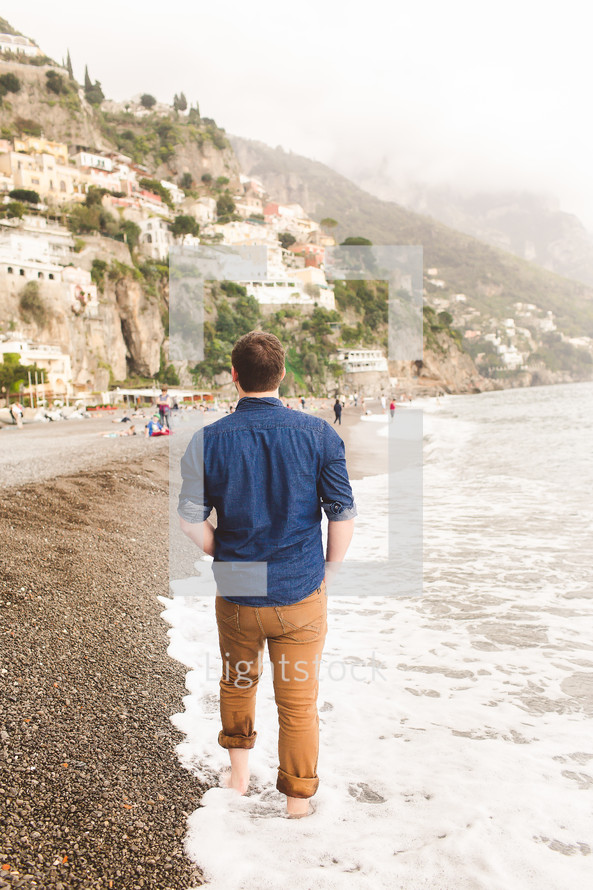 man walking on a beach along an Italian shoreline 