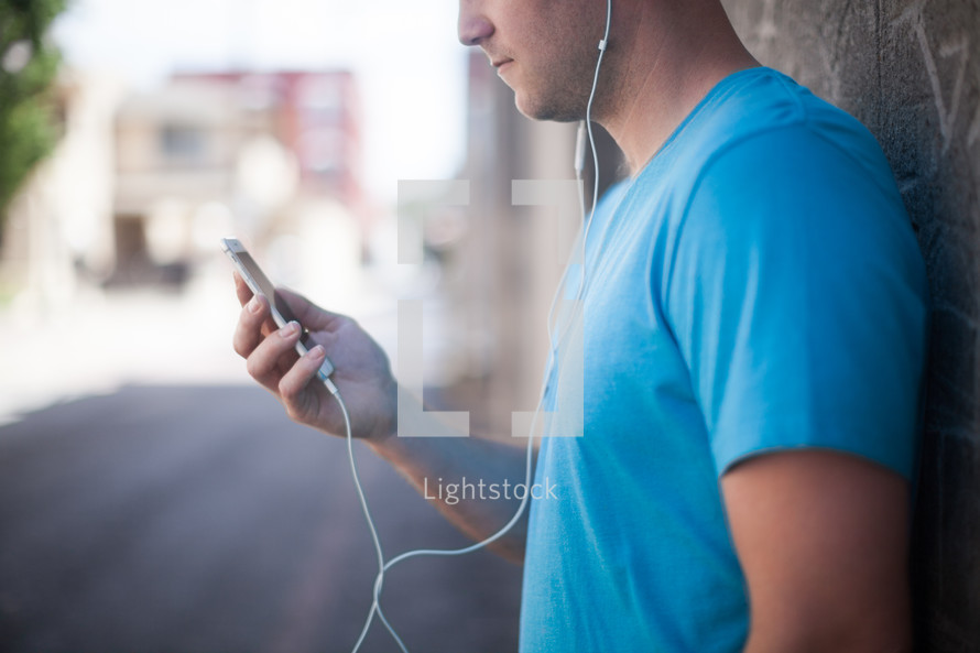 man walking in an alley listening to an iPod 