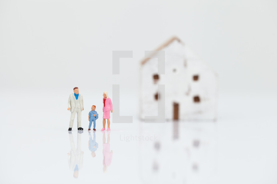 miniature figurines of a family in front of a house 