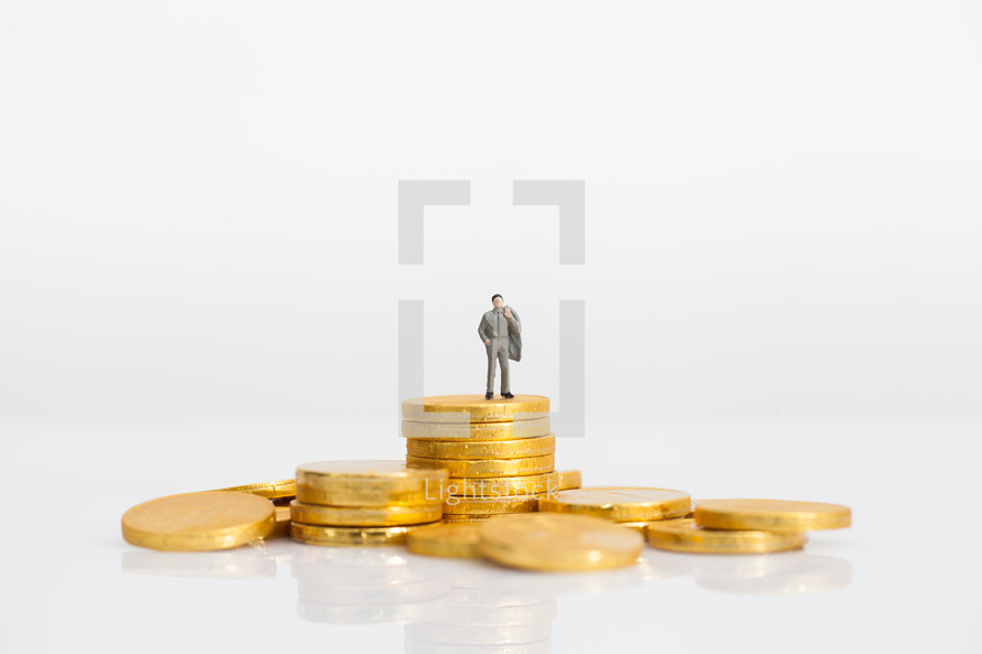 a miniature figurine standing on gold coins 