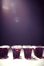 A light shins on several rows of communion cups filled with wine