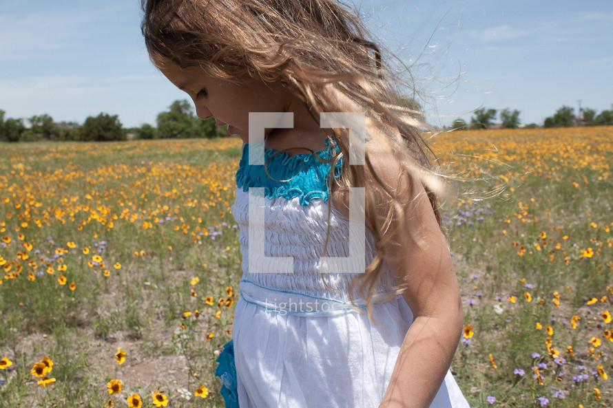a young girl walking in a field of wildflowers 