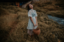 a young woman holding a basket standing outdoors 