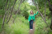 woman standing on a path in a forest 