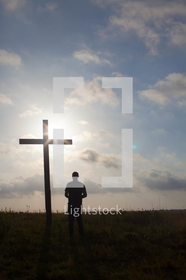 a man praying in front of a cross
