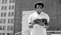 an African American man standing reading a Bible in a city 