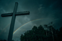 cross and rainbow under gray skies 