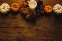Pumpkins and a candle on a wooden table -- fall decor.