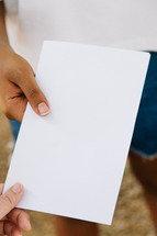 Close up of a woman holding out a blank flyer.