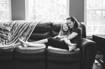 a mother and daughter snuggling on a couch 